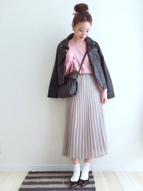 ピンクのトップスにベージュのプリーツスカートを穿いた女性