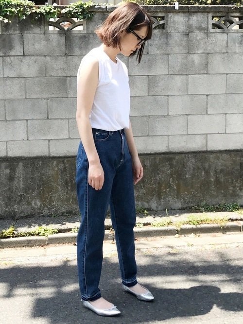 白いタンクトップにデニムを穿いた女性