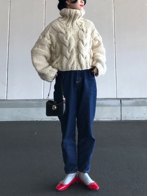 白いタートルネックニットにデニムを穿いた女性