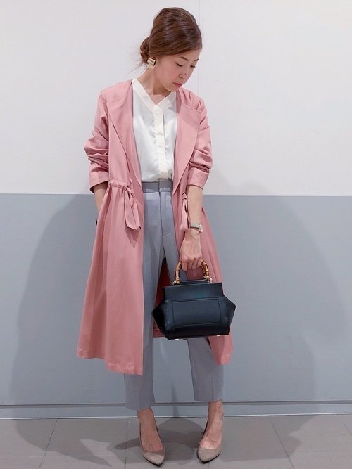 オフィスコーデにピンクのコートを着た女性