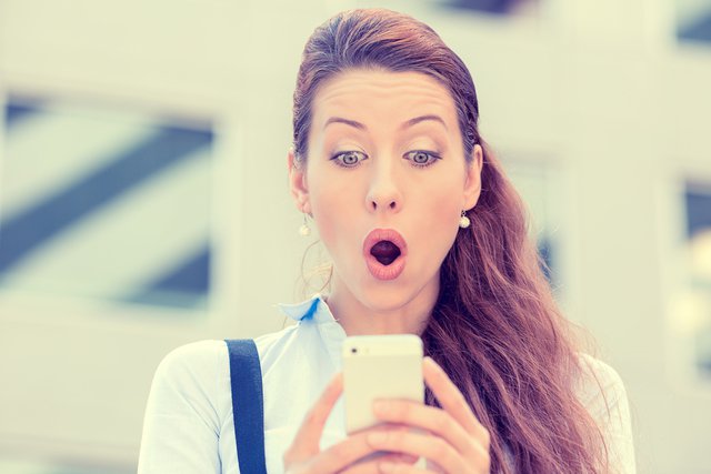 スマホを見て驚く女性